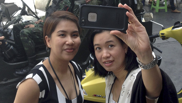 Residents stop to take a photograph of themselves at a military checkpoint in central Bangkok, Thailand, Tuesday, May 20, 2014. Thailand's army declared martial law in a surprise announcement before dawn Tuesday that it said was aimed at keeping the country stable after six months of sometimes violent political unrest. The military, however, denied a coup d'etat was underway. AP