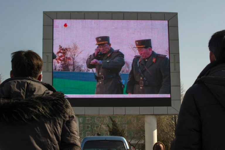 People watch news footage of a missile launch on a giant television screen outside the main railway station in Pyongyang on March 7, 2017. Nuclear-armed North Korea said its missile launches were training for a strike on US bases in Japan, as global condemnation of the regime swelled. / AFP PHOTO / KIM Won-Jin