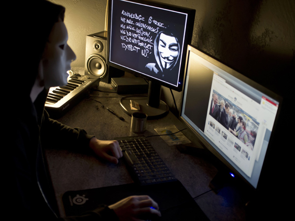 A masked hacker, part of the Anonymous group, hacks the French presidential Elysee Palace website on January 20, 2012 near the eastern city of Lyon. Anonymous, which briefly knocked the FBI and Justice Department websites offline in retaliation for the US shutdown of file-sharing site Megaupload, is a shadowy group of international hackers with no central hierarchy. JEAN-PHILIPPE KSIAZEK/AFP PHOTO 