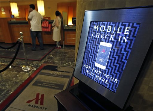In this Oct. 14, 2014 photo, a mobile check-in option is offered for travelers at the main check-in counter at the Marriott Marquis Times Square hotel in New York.  AP PHOTO/KATHY WILLENS