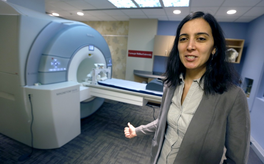 Leila Wehbe, a Ph.D. student at Carnegie Mellon University in Pittsburgh, talks about an experiment that used brain scans made in this brain-scanning MRI machine on campus, Wednesday, Nov. 26, 2014. Volunteers where scanned as each word of a chapter of "Harry Potter and the Sorcerer's Stone" was flashed for half a second onto a screen inside the machine. Images showing combinations of data and graphics were collected. (AP Photo/Keith Srakocic)