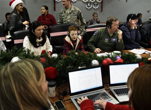 In this Dec. 24, 2012 file photo, U.S. Air Force Brig. Gen. Richard Scobie, right, his son Andrew, center, and wife, Janis, all take phone calls from children asking where Santa is and when he will deliver presents to their house, during the annual NORAD Tracks Santa Operation, at the North American Aerospace Defense Command, or NORAD, at Peterson Air Force Base, Colorado. AP