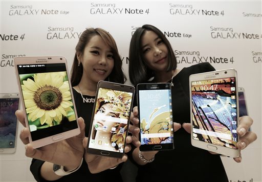 In this Sept. 24, 2014 file photo, Models pose with Samsung Electronics Co.'s latest Galaxy Note 4 and Galaxy Note Edge smartphones as they are unveiled in Seoul, South Korea. By the end of the year, there are expected to be about 7 billion cell phone subscriptions _ about the same as the world’s population. (AP Photo/Ahn Young-joon, File)