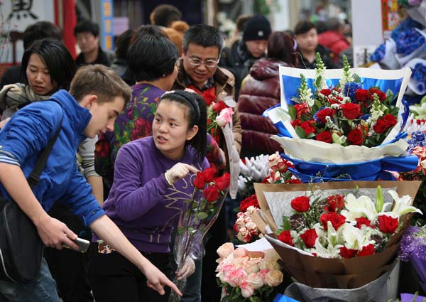 A man asks about the price of roses at Laitai Flower Market in Beijing on Friday ahead of Valentine's Day on Saturday. CHINA DAILY