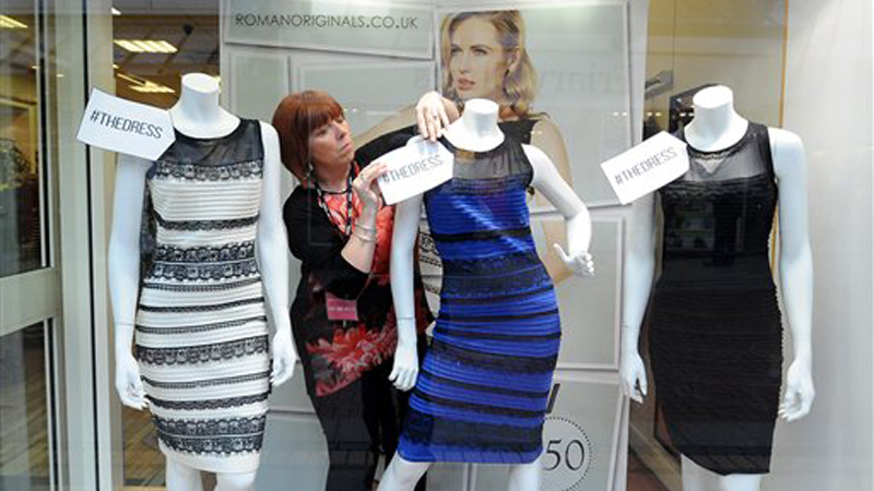 Shop manager Debbie Armstrong adjusts a two tone dress in a window display of a shop in Lichfield, England, Friday. It's the dress that's beating the Internet black and blue. Or should that be gold and white? AP 