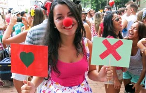 Luiza Rocha, a 22-year-old university student, holds up placards with symbols used on the hookup app Tinder at the Tinder-themed debut street party "Match Comigo" in Rio de Janeiro, Brazil, Monday, Feb. 16, 2015. The popular dating app which allows smartphone users to find a partner by swiping on a picture, launched a premium, paid subscription version of the service Monday, March 2.  AP PHOTO/JENNY BARCHFIELD 