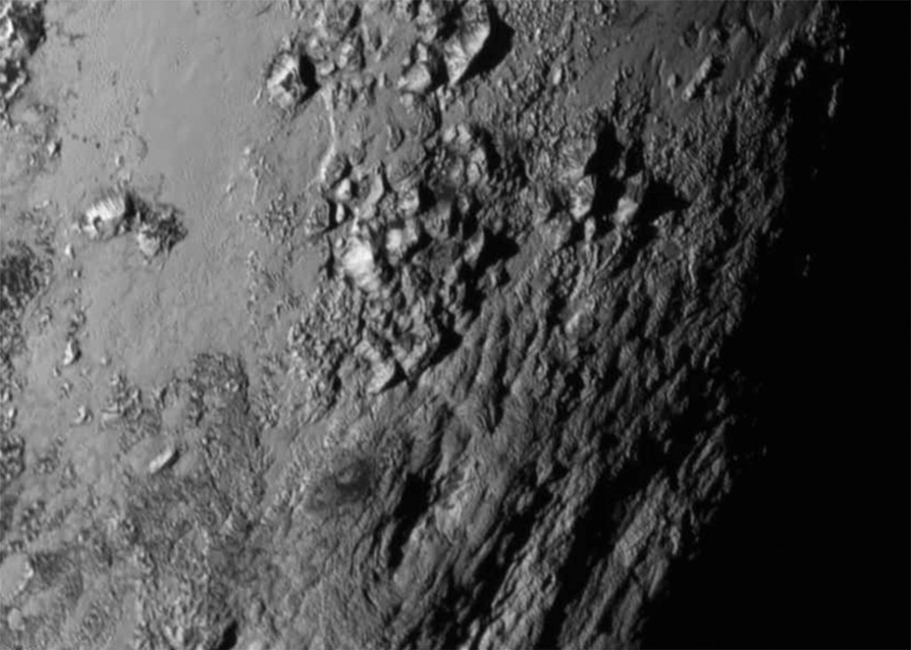 This Tuesday, July 14, 2015 image provided by NASA on Wednesday shows a region near Pluto's equator with a range of mountains captured by the New Horizons spacecraft. (NASA/JHUAPL/SwRI via AP)