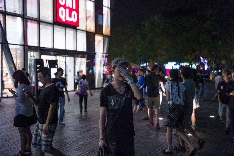 In this picture taken on July 15, 2015, people gather in front of a Uniqlo clothes store in Beijing. Chinese Communist authorities have said the distribution of a sex tape purportedly shot in a fitting room in one of Beijing's trendiest shopping malls is "against socialist core values", after the footage went viral.  AFP PHOTO / FRED DUFOUR