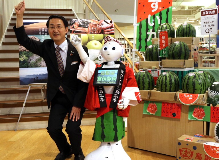 Japanese telecom giant Softbank's humanoid robot Pepper (R) gestures alongside Tottori Prefecture Governor Shinji Hirai (L) as they promote the sale of watermelons produced in Japan's Tottori prefecture, at a shop promoting produce from the prefecture, in Tokyo on July 1, 2015. Softbank's subsidiary "cocoro SB" -- the world's first robot dispatch service -- has hired out Pepper as a sales promotion staff member for 1,500 yen (12.5 USD) an hour.       AFP 
