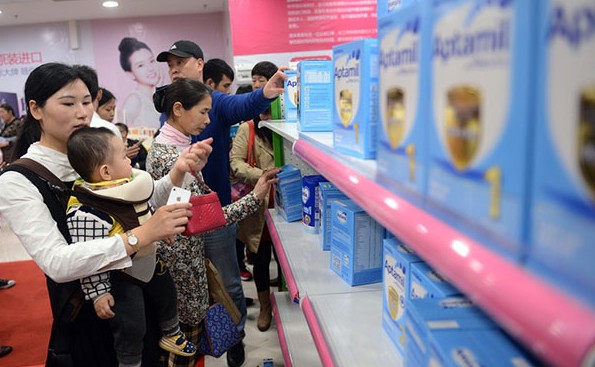 A Chinese mom shops for diapers while carrying her baby in a supermarket in Guangzhou, Guangdong province.File photo by China Daily/IC