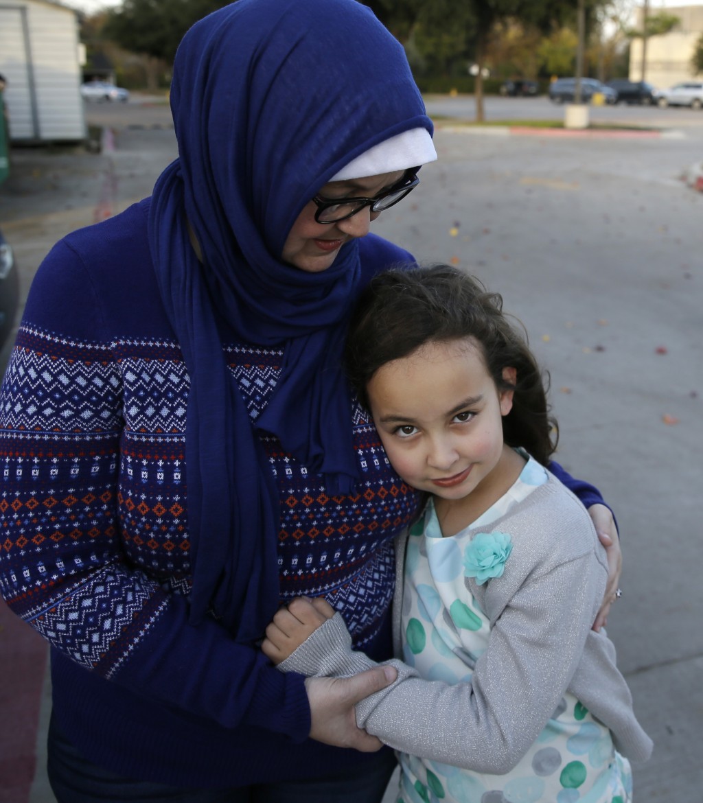 Sofia Yassini, 8, right, gets a hug from her mother Melissa Yassini after posing for a photo outsider a mosque in Richardson, Texas, Friday, Dec. 11, 2015. After seeing presidential candidate Donald Trump call on television for barring Muslims from entering the country, the 8-year-old started packing her favorite things and checking the locks on the doors because, in her mind, Donald Trump’s push to ban Muslims meant the Army would come and rip her family from their home. Trumps' remarks in the wake of the Dec. 2  shooting attack in San Bernardino, Calif., have stoked similar fears in Muslim children across the U.S. Their young minds, parents say, are confused about who the screaming man on TV is, what he’s saying about their faith and why thousands of their fellow Americans are cheering him on. (AP Photo/LM Otero)