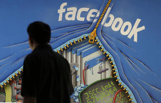 In this June 11, 2014, file photo, a man walks past a mural in an office on the Facebook campus in Menlo Park, Calif. On Thursday, May 12, 2016, Facebook pulled back the curtain on how its Trending Topics feature works, a reaction to a report that suggested Facebook downplays conservative news subjects. AP FILE PHOTO