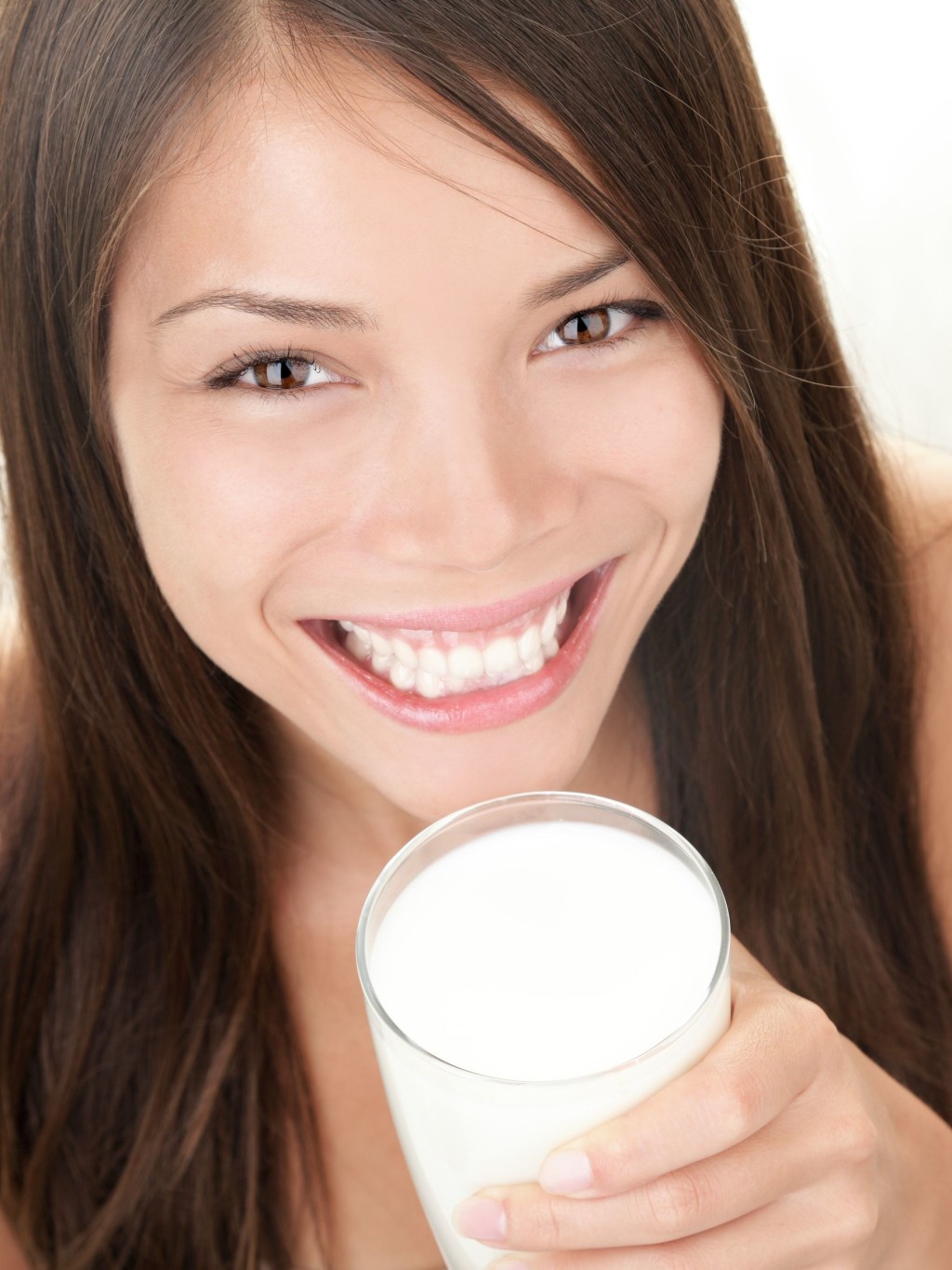 7780041 - milk - woman drinking milk. happy smiling beautiful young woman enjoying a glass milk while smiling looking at camera