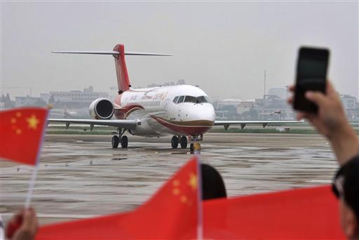 In this June 28, 2016, file photo, people wave Chinese flags and take photos as a Chengdu Airlines ARJ21-700 regional jet is taxied after landing at the Hongqiao Airport in Shanghai. AP