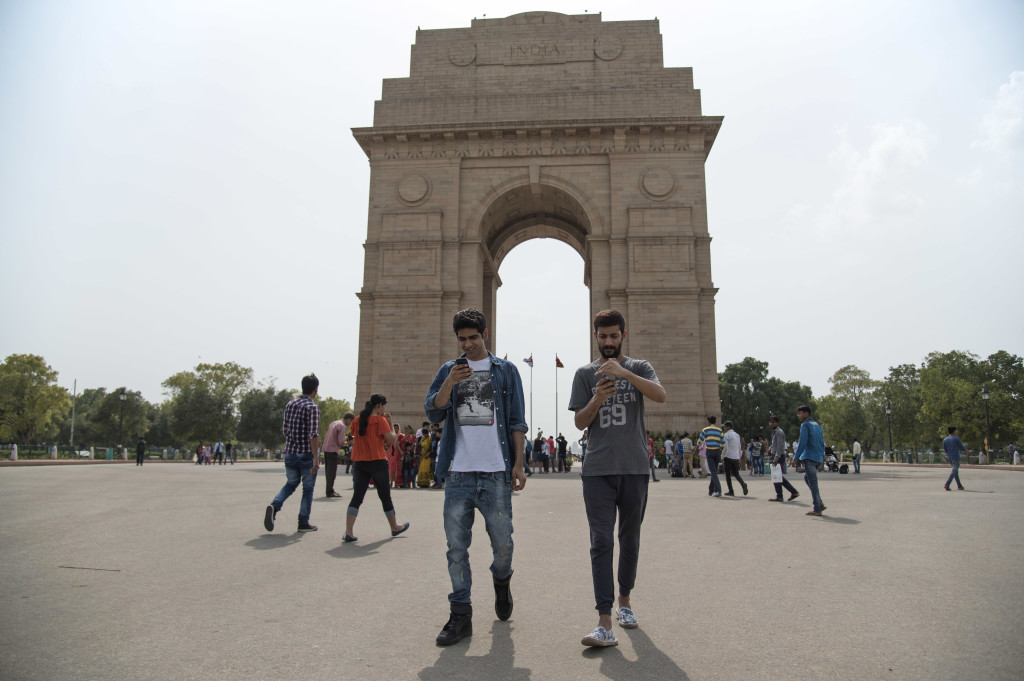 Shivanu Mandal, left, and Geet Singh look at their screens as they play "Pokemon Go" in front of the landmark India Gate monument in New Delhi, India, Friday, July 22, 2016. Fans have found a way to access the game although it has not been released in the country yet. (AP Photo/Thomas Cytrynowicz)
