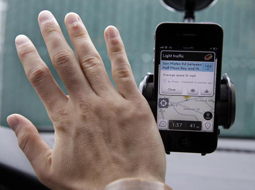 In this March 15, 2012, file photo, Ben Gleitzman waves his hand over a traffic and navigation app called Waze on his Apple iPhone in a Menlo Park, Calif., parking lot during a demonstration showing traffic conditions on the display. AP
