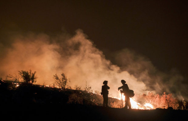 File - In this Aug. 9, 2018, file photo, firefighters keep watch the Holy Fire burning in the Cleveland National Forest in Lake Elsinore, Calif. Researchers have expanded a health-monitoring study of wildland firefighters after a previous study found season-long health declines and deteriorating reaction times. (AP Photo/Ringo H.W. Chiu, File)