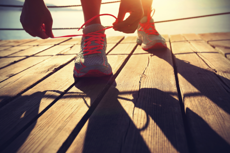 healthy lifestyle sports woman tying shoelace on wooden boardwalk sunrise seaside