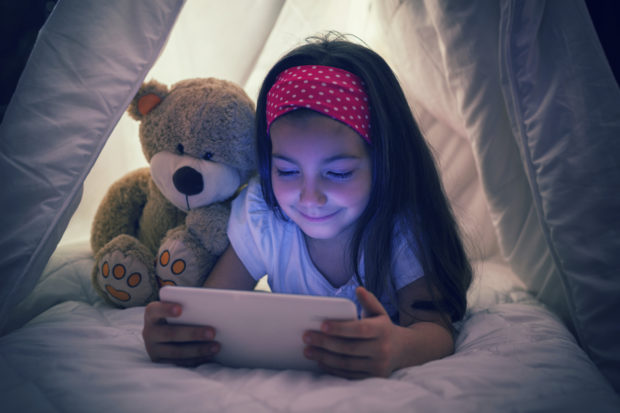 Little Girl Using Digital Tablet in Bed