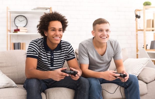 Diverse teenage boys playing game console at home