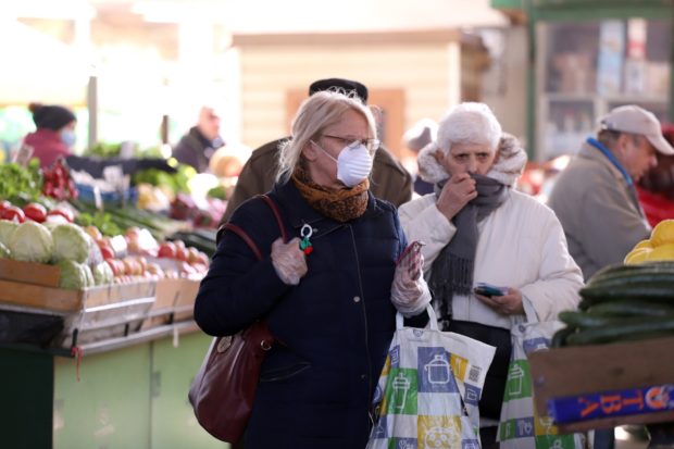People, wearing face masks for protection, are shopping vegetables and fruits at marketplace