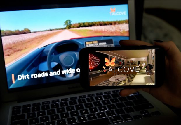 This illustration picture shows a virtual road trip on a computer and the travel application logo from Alcove displayed on a smartphone in Arlington, Virginia on March 19, 2021. - Strict lockdowns and travel limitations during the pandemic have sparked fresh interest in immersive virtual travel experiences, which have become more accessible and affordable with new apps and VR hardware. (Photo by OLIVIER DOULIERY / AFP)