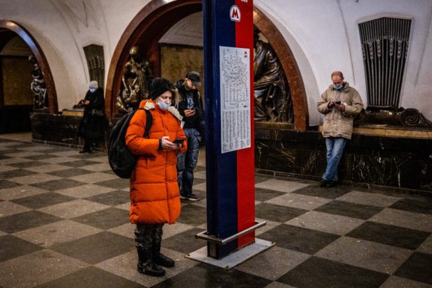 Commuters use their mobile phones at Ploschad Revolyutsii metro station in Moscow on March 10, 2021. - Russia said on March 10, 2021, it was disrupting Twitter's services because the platform had failed to remove "illegal" content, the latest in a series of moves exerting control over foreign tech giants. The Russian government has been clamping down on sites including Facebook, Twitter and YouTube in recent months for hosting content supporting jailed opposition figure Alexei Navalny
