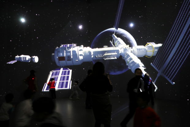 Visitors stand near a giant screen displaying the images of the Tianhe space station at an exhibition featuring the development of China's space exploration on the country's Space Day at China Science and Technology Museum in Beijing, China April 24, 2021