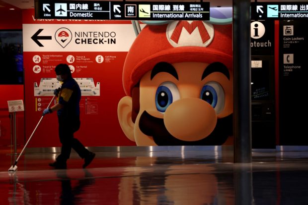 A cleaner mops the floor in front of a Nintendo’s Super Mario game character decoration at Narita Airport in China prefecture on June 1, 2021. 