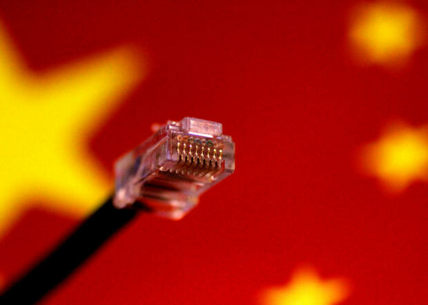 FILE PHOTO: A computer network cable is seen above a Chinese flag in this July 12, 2017 illustration photo.   REUTERS/Thomas White/Illustration; internet cable