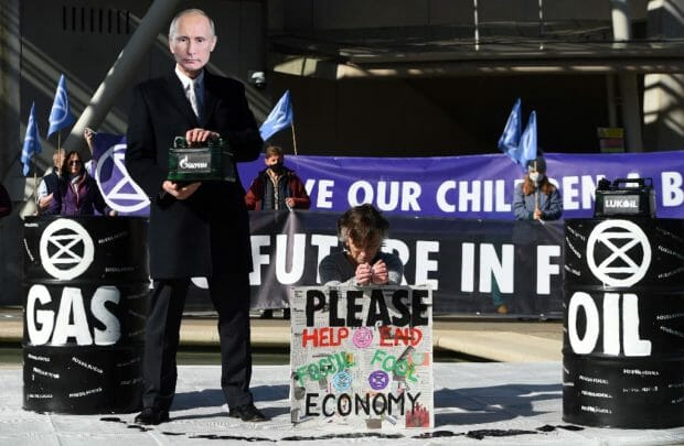 An activist from the Extinction Rebellion protest group, wearing a mask depicting Russian President Vladimir Putin, holds a 'Gazprom' branded fuel container, as they demonstrate against fossil fuel use, outside of the Scottish Parliament Building in Edinburgh on April 1, 2022. (Photo by ANDY BUCHANAN / AFP)