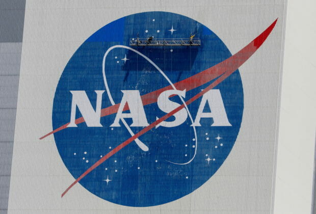 FILE PHOTO: Workers pressure wash the logo of NASA on the Vehicle Assembly Building before SpaceX will send two NASA astronauts to the International Space Station aboard its Falcon 9 rocket, at the Kennedy Space Center in Cape Canaveral, Florida, U.S., May 19, 2020. REUTERS/Joe Skipper