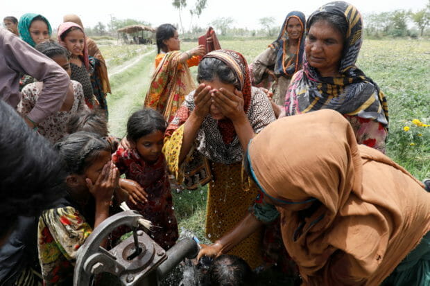 Women and children wash themselves after work at a muskmelon farm, during a heatwave, at a hand pump on the outskirts of Jacobabad, Pakistan, May 17, 2022. Last month Jacobabad became the hottest city on Earth. Women are especially vulnerable to rising temperatures in poor countries on the frontlines of climate change because many have little choice but to work through their pregnancies and soon after giving birth, according to interviews with more than a dozen female residents in the Jacobabad area as well as half a dozen development and human rights experts. REUTERS/Akhtar Soomro