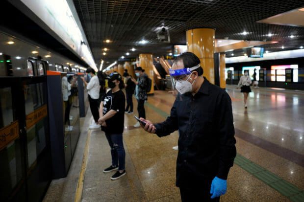 FILE PHOTO: A man wearing protective gear checks his mobile phone at a subway station, after the lockdown placed to curb the coronavirus disease (COVID-19) outbreak was lifted in Shanghai, China June 2, 2022. REUTERS/Aly Song