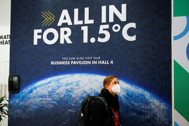 FILE PHOTO: A delegate walks past a climate change poster at the UN Climate Change Conference (COP26) in Glasgow, Scotland, Britain, November 1, 2021. REUTERS/Phil Noble
