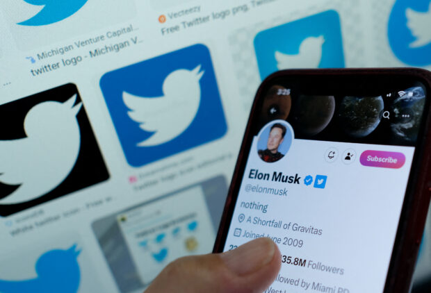 This illustration photo taken in Los Angeles on April 20, 2023, shows Elon Musk's blue tick next to his name on a smartphone. - And so The Great Sorting has begun. Elon Musk's long promised move to strip un-paid-for Blue Ticks from Twitter users swung into action on April 20, 2023. Like some kind of Bibilical parable in which sheep and goats are separated, hundreds of high profile accounts were put on Elon's left side, while a handful of others were gathered on his right. (Photo by Chris DELMAS / AFP)