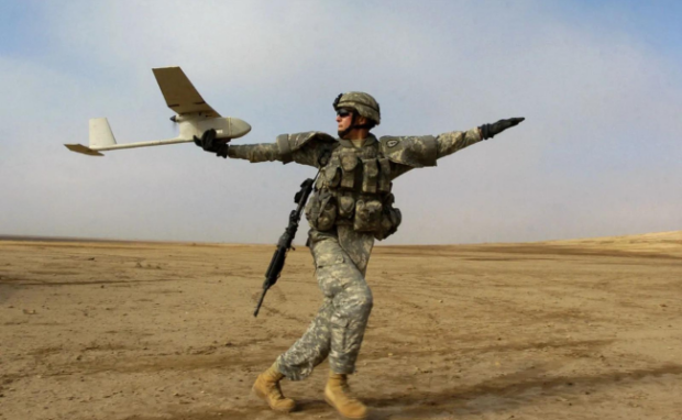 Military personnel launching a drone.