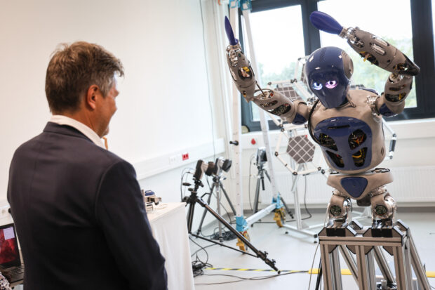 German Minister of Economics and Climate Protection Robert Habeck (L) stands in front of a dancing robot at the Robotics Innovation Center of the German Research Center for Artificial Intelligence (DFKI) in Bremen, Germany, on September 14, 2023. German Minister of Economics and Climate Protection Robert Habeck visits the Robotics Innovation Center of the German Research Center for Artificial Intelligence and the Fraunhofer Institute for Manufacturing Technology and Advanced Materials (IFAM). (Photo by FOCKE STRANGMANN / AFP)