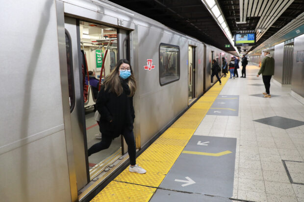 A woman wearing a mask, amid rising global numbers of novel coronavirus disease (COVID-19) cases, exits a subway train in Toronto