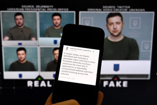 This illustration photo taken on January 30, 2023 shows a phone screen displaying a statement from the head of security policy at Meta with a fake video (R) of Ukrainian President Volodymyr Zelensky calling on his soldiers to lay down their weapons shown in the background, in Washington, DC. 