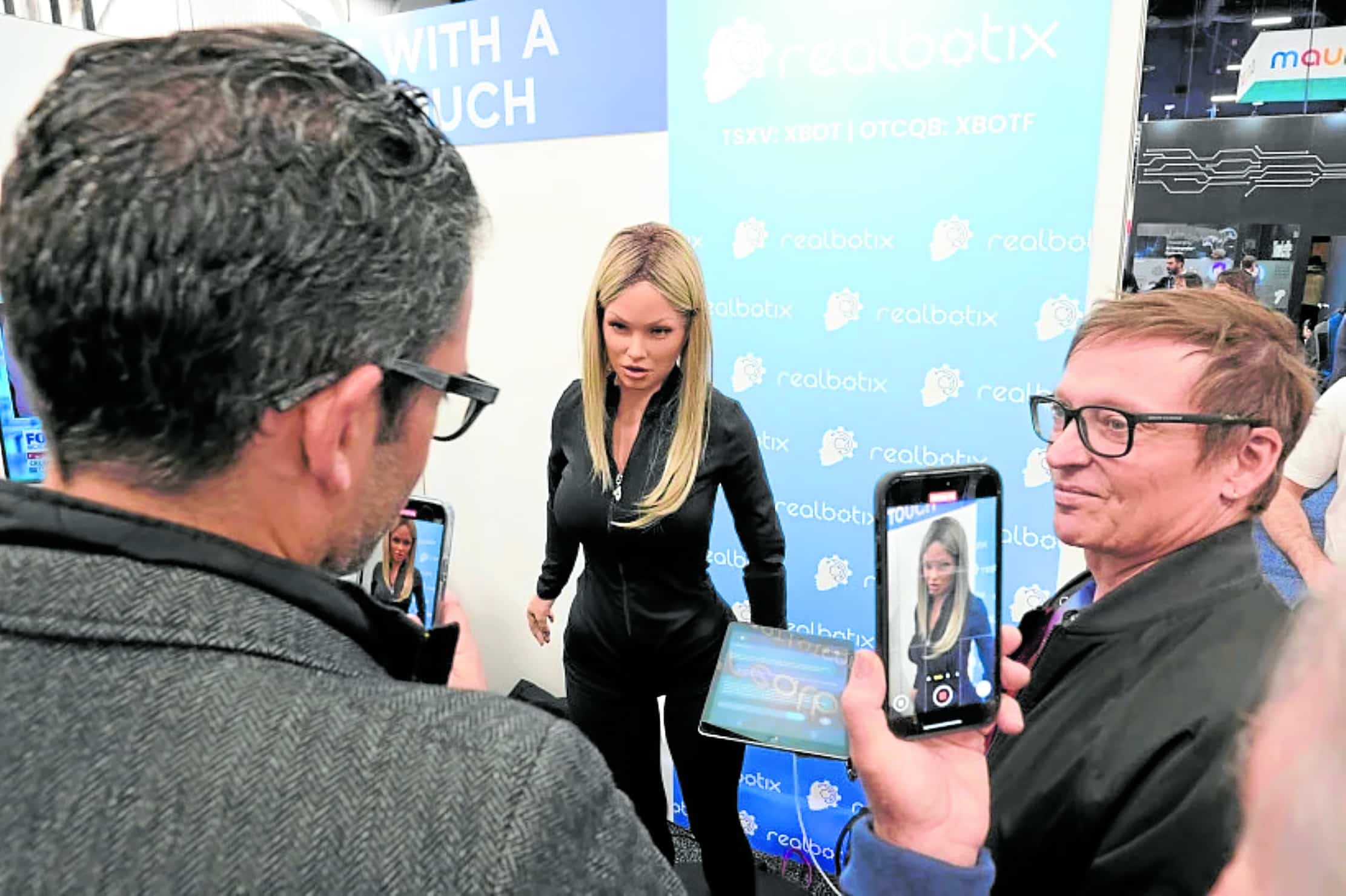 ‘SALLY’ CAN’T HACK IT A Realbotix humanoid robot (center)speaks with attendees at a Realbotix booth during the CEStech show in Las Vegas on Jan. 8, 2025.